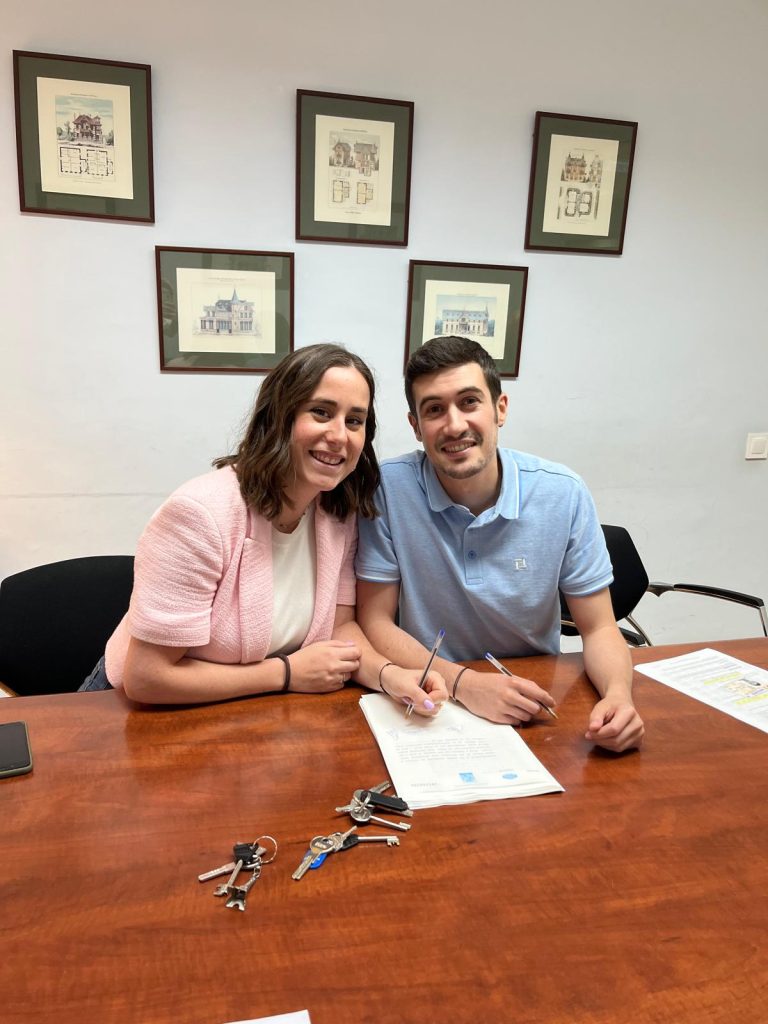 Pareja de clientes de FIKA Finance firmando su hipoteca con las llaves de su nueva casa